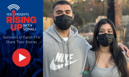 Two people wearing black masks stand beside each other and look at the camera